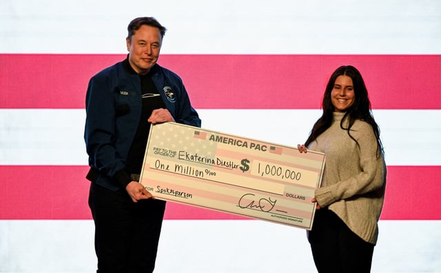 U.S. President Donald Trump's adviser Elon Musk gives a check to an audience member during a rally in support of a conservative state Supreme Court candidate of an April 1 election in Green Bay, Wisconsin, U.S. March 30, 2025.  REUTERS/Vincent Alban/File Photo