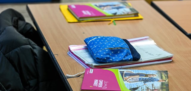 Hefter, Lehrbücher und Federmappen liegen in einem Klassenzimmer einer Schule