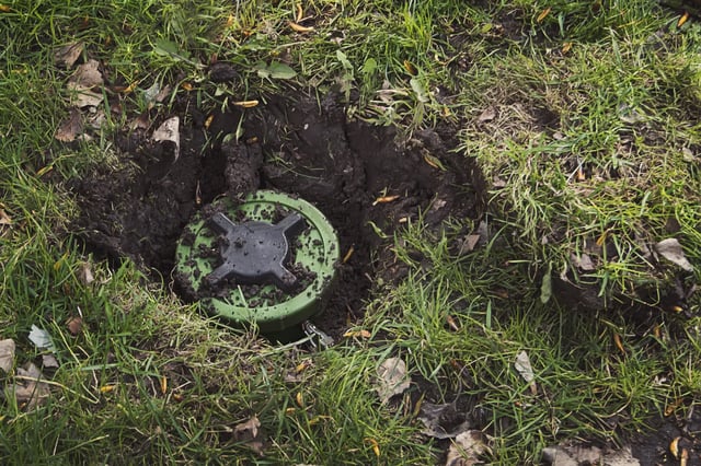 Anti-personnel mine in the ground. dig a mine. antipersonnel mine. mining. Demining. Minefield