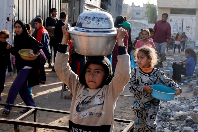Palestinian children receive food cooked by a charity kitchen, during the Muslim holy month of Ramadan, in Rafah, in the southern Gaza Strip, March 13, 2025. REUTERS/Hatem Khaled/File Photo