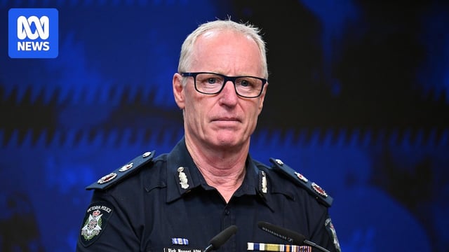 Rick Nugent, dressed in a police uniform, stands a lectern indoors.