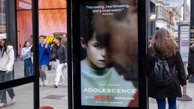 Passing people interacting with an advertising poster on a bus shelter for the Netflix drama &#39;Adolescence&#39;, the story of which is sparking conversations in public and government around the subject of toxic masculinity and children&#39;s access to dangerous and misogynistic content on the internet and social media on 23rd March 2025 in London, United Kingdom.