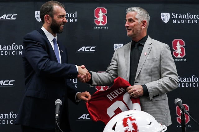 Stanford football general manager GM Andrew Luck, left, shakes hands with Frank Reich as Reich is introduced Tuesday as Cardinal football’s interim head coach at the Arrillaga Family Sports Center. Reich, a former NFL quarterback and head coach, replaces Troy Taylor, who was fired March 25.