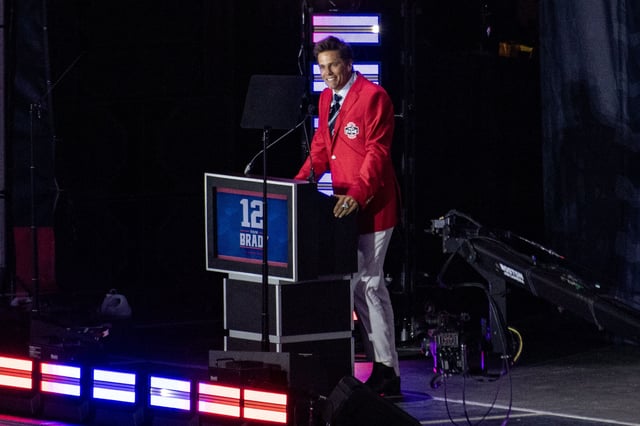 Former New England Patriots quarterback Tom Brady wears his red Patriots Hall of Fame induction jacket as he speaks during the 2024 induction ceremony at Gillette Stadium in Foxborough, Massachusetts.