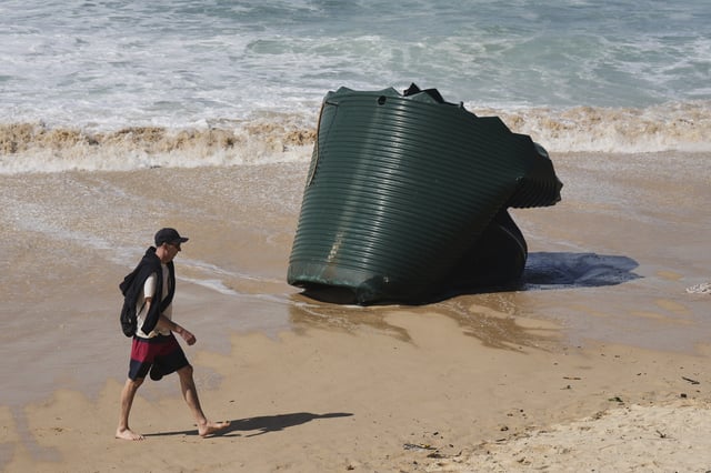 A man walks past a water tank washed onto Sydney's Bondi Beach Wednesday, April 2, 2025. (AP Photo/Mark Baker)