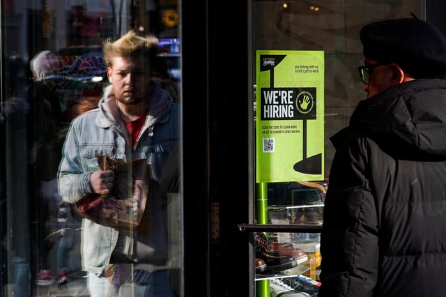 A "we're hiring" poster is seen in a window as people visit a retail store during the holiday season in New York City, U.S., December 21, 2022. REUTERS/Eduardo Munoz/File Photo