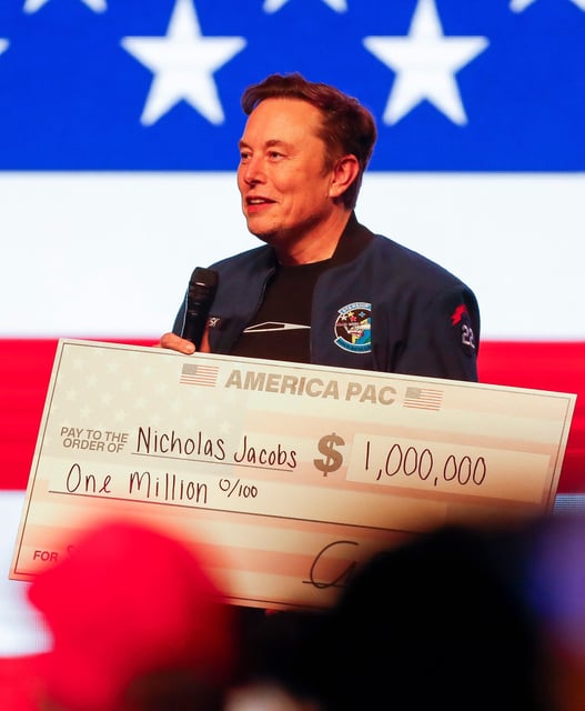 Billionaire Elon Musk presents a check for $1 million made out to Nicholas Jacobs during a town hall on Sunday, March 30, 2025, at the KI Convention Center in Green Bay, Wis.