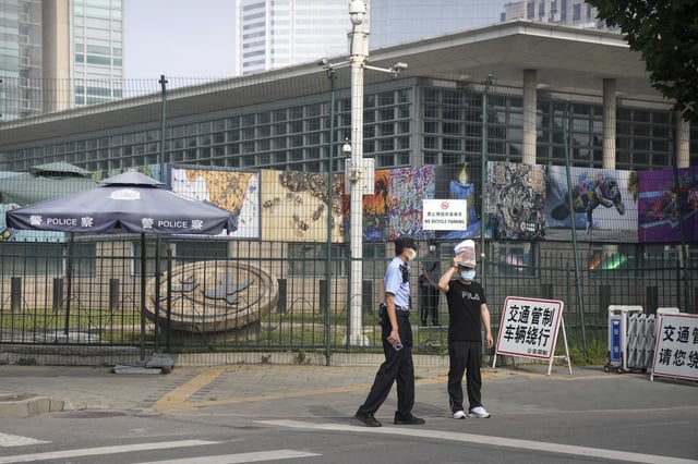 FILE - Uniformed and plainclothes security officers stand guard outside the U.S. Embassy in Beijing, Aug. 3, 2022. (AP Photo/Mark Schiefelbein, File)