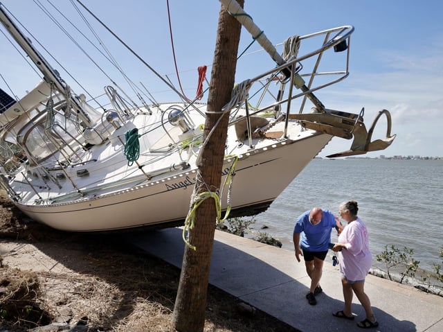 Keith and his wife Angel, check on their sailboat that ended up on the sidewalk near Sarasota Bay after Hurricane Milton made landfall in Sarasota on Thursday, Oct. 10, 2024. (Carline Jean/South Florida Sun Sentinel)