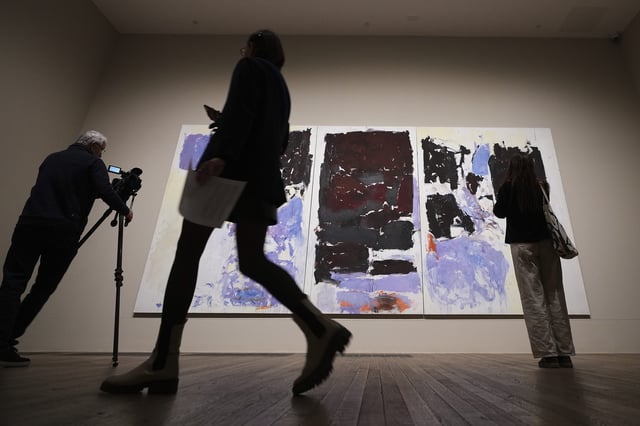 People gather around a painting by artist Joan Mitchell called Iva 1973, donated by Jorge M. and Darlene Perez, at the Tate Modern in London, Thursday, April 3, 2025. (AP Photo/Kirsty Wigglesworth)