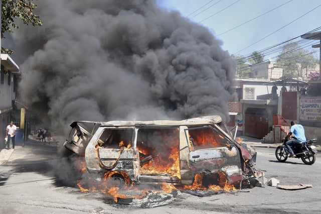 A motorcyclist rides past a burning car during a protest against insecurity in Port-au-Prince, Haiti, Wednesday, April 2, 2025. (AP Photo/Odelyn Joseph)