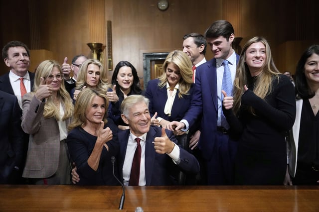 Dr. Mehmet Oz, President Donald Trump's pick to lead the Centers for Medicare and Medicaid Services, seated right, gives a thumbs-up alongside his wife Lisa Oz, seated left, with friends and family after he testified at his confirmation hearing before the Senate Finance Committee, on Capitol Hill in Washington, Friday, March 14, 2025. (AP Photo/Ben Curtis)