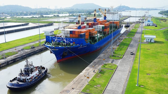 A cargo ship and tugboat sail through the Cocoli Locks at the Panama Canal