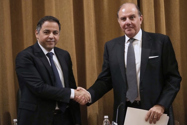 Karim Souaid, the newly appointed Lebanon's central bank governor, right, shakes hands with the incoming interim governor Wassim Mansouri, during a handover taking office ceremony, in Beirut, Lebanon, Friday, April 4, 2025. (AP Photo/Hussein Malla)