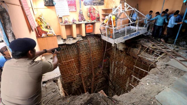 A police officer takes pictures during rescue operations after the roof of a stepwell in a temple complex collapsed in Indore on 30 March 2023. (Reuters)