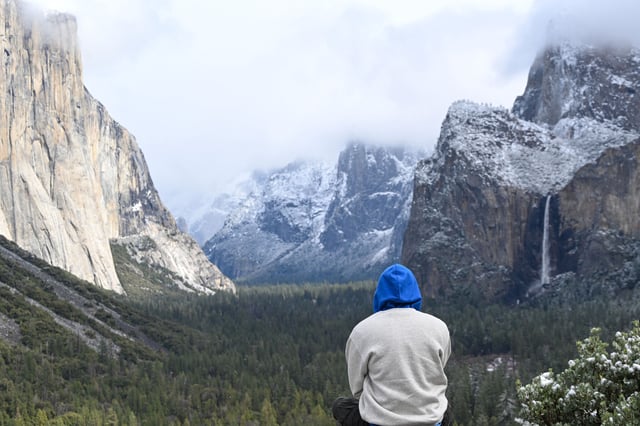 A visitor takes in the scenery at Tunnel View during snowy weather in Yosemite National Park, Calif., on March 6, 2025.