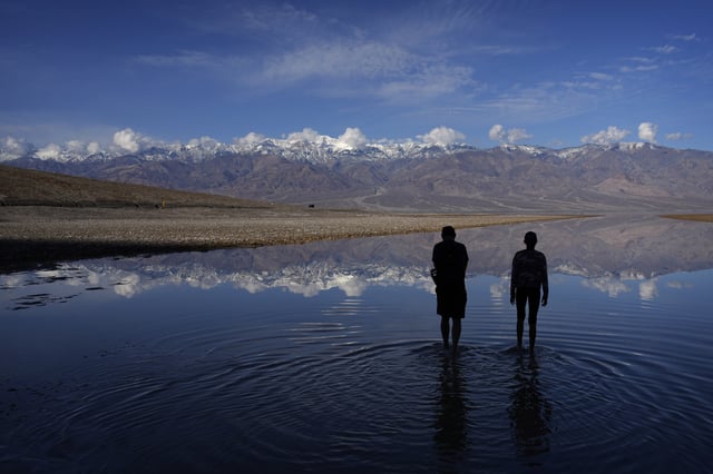 FILE - People wade into water at Badwater Basin in Death Valley National Park, Calif., on Thursday, Feb. 22, 2024. The basin, normally a salt flat, has filled from rain over the previous few months. (AP Photo/John Locher, File)