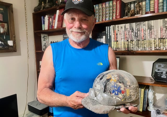 Retired coal miner Stanley "Goose" Stewart holds a helmet he wore inside the Upper Big Branch mine when it blew up on April 5, 2010, killing 29 men, as he stands for a portrait at his home in Orgas, W.Va., on Wednesday, April 2, 2025. (AP Photo/John Raby)