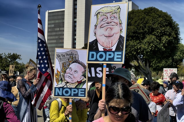 FILE - Protesters carry signs and chant slogans in protest to the policies of President Donald Trump and Elon Musk across from the Federal Building in the Westwood section of Los Angeles, Saturday, March 22, 2025. (AP Photo/Richard Vogel, File)