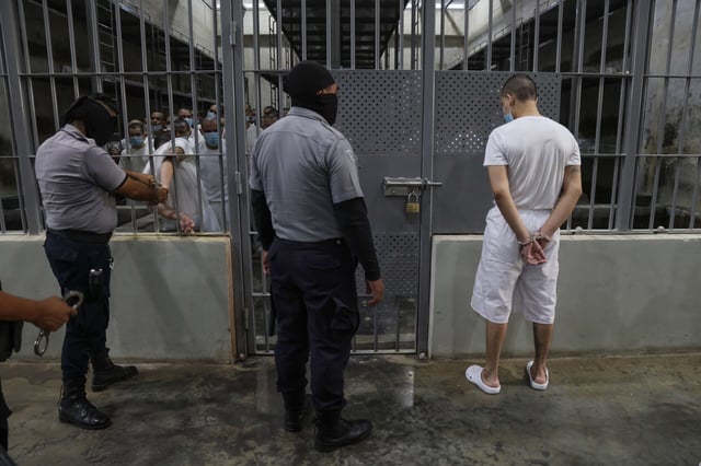 Prison officers remove handcuffs from a prisoner to enter a cell at maximum security penitentiary CECOT on April 4, 2025, in Tecoluca, San Vicente, El Salvador.