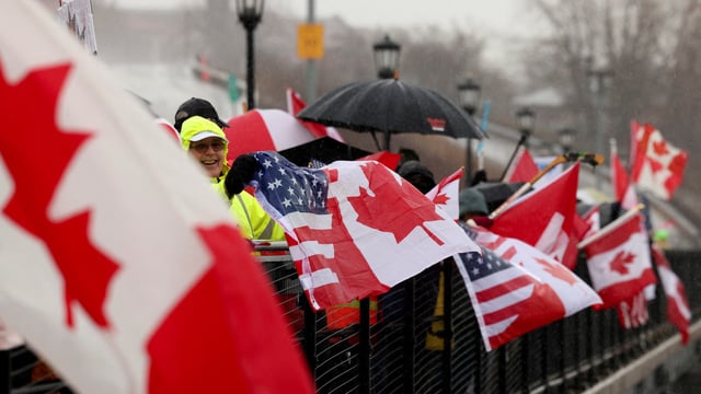 People hold flags as they protest in solidarity with Canada amid uncertainty over tariffs policy, near the Canada-US border crossing in Buffalo, New York