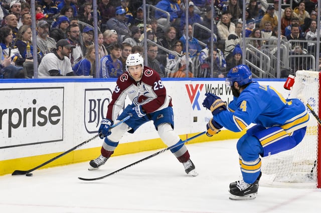 Apr 5, 2025; St. Louis, Missouri, USA;  Colorado Avalanche center Nathan MacKinnon (29) controls the puck as St. Louis Blues defenseman Nick Leddy (4) defends during the third period at Enterprise Center. Mandatory Credit: Jeff Curry-Imagn Images
