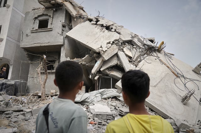 Children look at the destroyed house of journalist Islam Meqdad, where she was killed along with her son and five other family members in an Israeli army strike in Khan Younis, southern Gaza Strip, Sunday, April 6, 2025. (AP Photo/Abdel Kareem Hana)