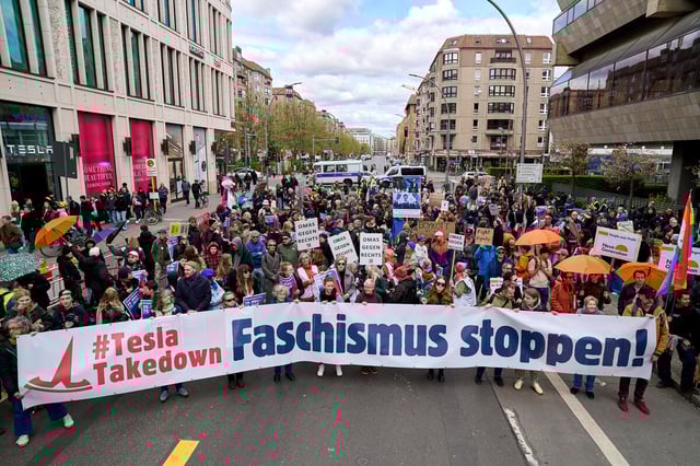 Protestierende gegen Tesla in Berlin mit dem Plakat "Faschismus stoppen"