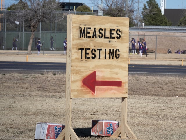 SEMINOLE, TEXAS - FEBRUARY 27: Signs point the way to measles testing in the parking lot of the Seminole Hospital District across from Wigwam Stadium on February 27, 2025 in Seminole, Texas. Eighty cases of measles have been reported in Gaines county with one death reported. (Photo by Jan Sonnenmair/Getty Images)