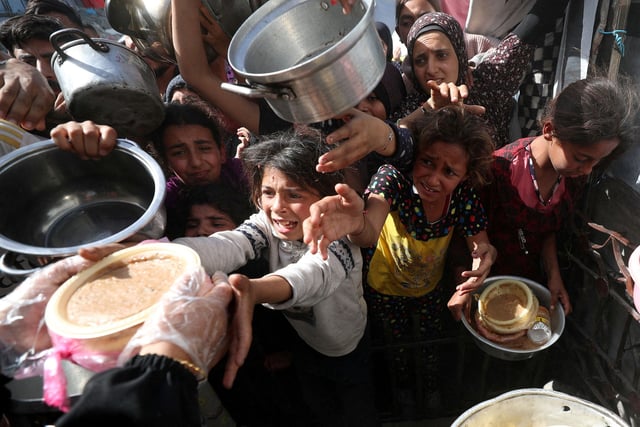 Palestinian children receive food cooked by a charity kitchen, in Beit Lahia, northern Gaza Strip, on Sunday.