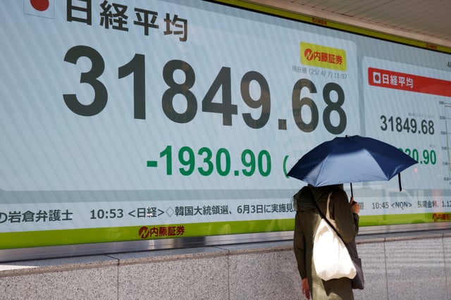 Un homme passe devant un tableau de cotations boursières dans une société de courtage à Tokyo, Japon, le 7 avril 2025.
