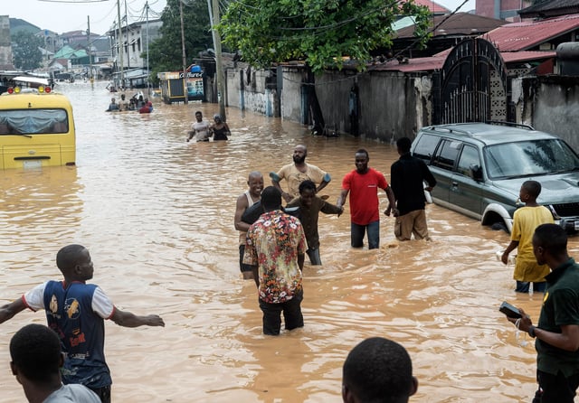People walk through the flooded streets of Kinshasa, Democratic Republic of Congo Sunday, April 6, 2025. (AP Photo/Samy Ntumba Shambuyi)