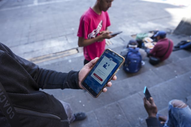 FILE - Venezuelan migrant Yender Romero shows the U.S. Customs and Border Protection (CBP) One app on his cell phone, which he said he used to apply for asylum in the U.S. and is waiting on an answer, at a migrant tent camp outside La Soledad church in Mexico City, Jan. 20, 2025. (AP Photo/Fernando Llano, File)