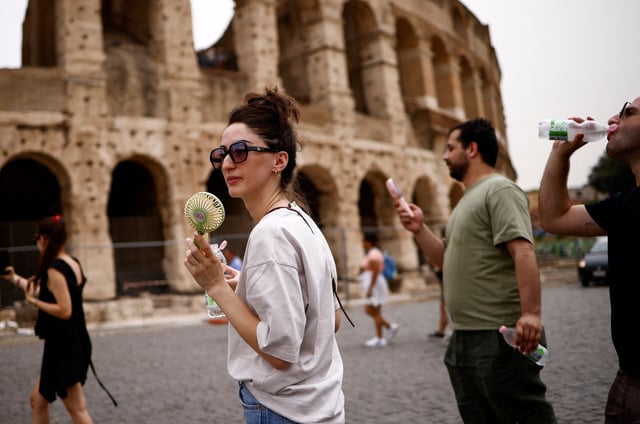 Dea from Georgia uses a fan to cool off as she walks near the Colosseum amid a heatwave in Rome, Italy, June 20, 2024. REUTERS/Guglielmo Mangiapane/File Photo