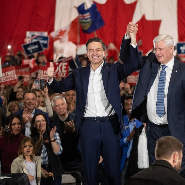 Former prime minister Stephen Harper, right, and Conservative Party Leader Pierre Poilievre raise hands at a rally in Edmonton on April 7, 2025.