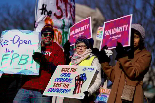 Consumer Financial Protection Bureau (CFPB) workers hold placards as they rally on the day of a hearing in a case on the Trump administration's mass firings of CFPB workers, outside the U.S. District Court in Washington, D.C., U.S., March 3, 2025. REUTERS/Kent Nishimura/File Photo