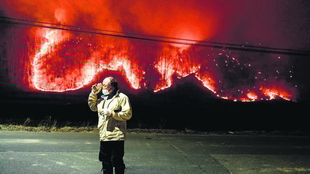 A man talks to his son on the phone under a streetlight on the road in front of his home as wildfires burn in Uiseong, South Korea, on March 24. (AFP)