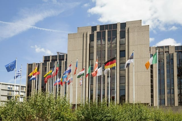 Vor einem großen Gebäude wehen viele europäische Flaggen