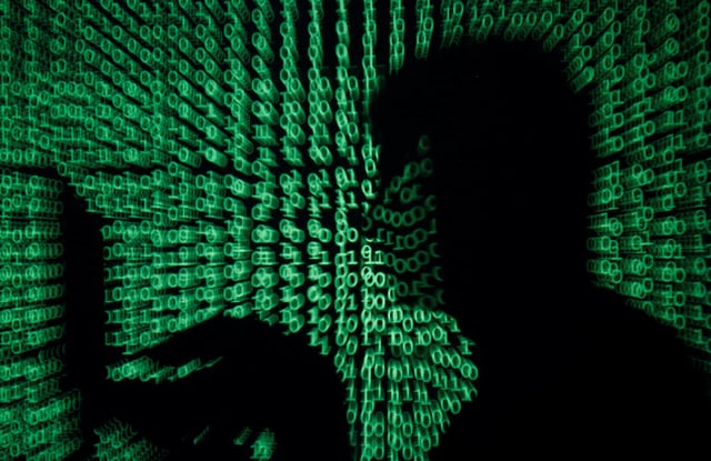 A man holds a laptop computer as cyber code is projected on him in this illustration picture taken on May 13, 2017.  REUTERS/Kacper Pempel/Illustration/File Photo