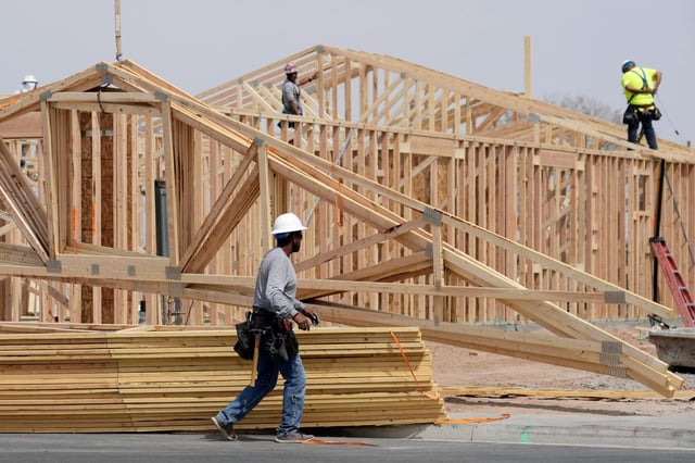 Construction workers install a lumber roof at a new home build Tuesday, April 1, 2025, in Laveen, Ariz. (AP Photo/Ross D. Franklin)