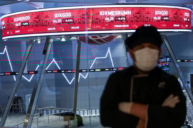 A man stands as an electronic board displays stocks in the background at the Indonesia Stock Exchange (IDX) in Jakarta, April 8, 2025. REUTERS/Willy Kurniawan/File Photo