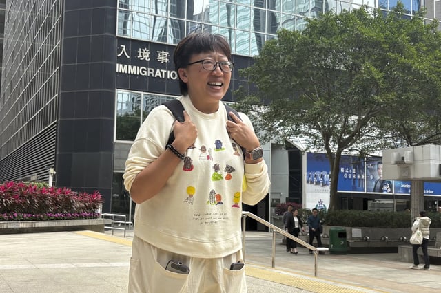 Hong Kong social worker Jackie Chen stands in front of the District Court building in Wan Chai, Hong Kong for journalists to take photographs ahead of her verdict hearing Tuesday, March 11, 2025. (AP Photo/Kanis Leung)