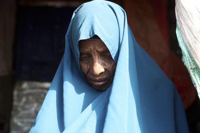 A Somali internally displaced (IDP) woman stands outside makeshift homes in Maslah camp, on the outskirts of Mogadishu, Somalia, Wednesday, April 9, 2025. (AP Photo/Farah Abdi Warsameh)