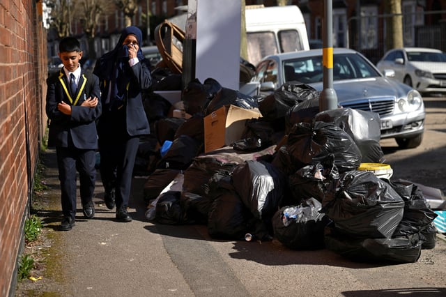 A school girl holds her nose due to the smell of a pile of rubbish on the street, as the strike action by Birmingham bin workers represented by the Unite union enters its fourth week, in Sparkhill, Birmingham, Britain, April 2, 2025. REUTERS/Jaimi Joy/ File Photo