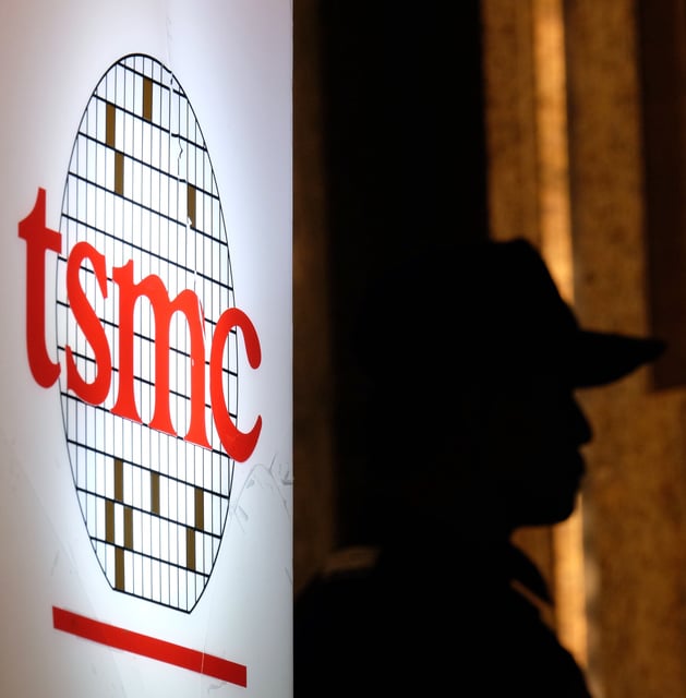 A security staff stands next to a logo of the Taiwan Semiconductor Manufacturing Co, (TSMC), during the investors conference in Taipei on July 16, 2014. TSMC, the world's biggest contract microchip maker, was to release second-quarter earnings results at an online conference. AFP PHOTO / SAM YEH (Photo credit should read SAM YEH/AFP/Getty Images)