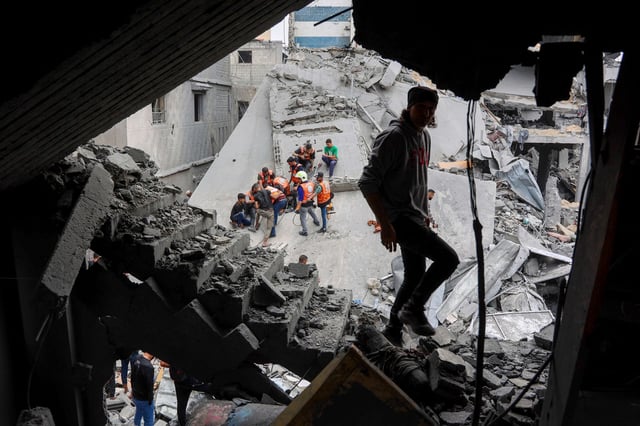 A man walks amids the rubble of a building as Palestinian rescuers work at the site of an Israeli strike on a residential area in Gaza City's Shujaiyya neighbourhood, on April 9, 2025.