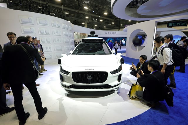 Attendees look over a Jaguar I-Pace equipped with a Waymo autonomous driving system at CES 2025, an annual consumer electronics trade show, in Las Vegas, Nevada, U.S., January 7, 2025.  REUTERS/Steve Marcus/File Photo