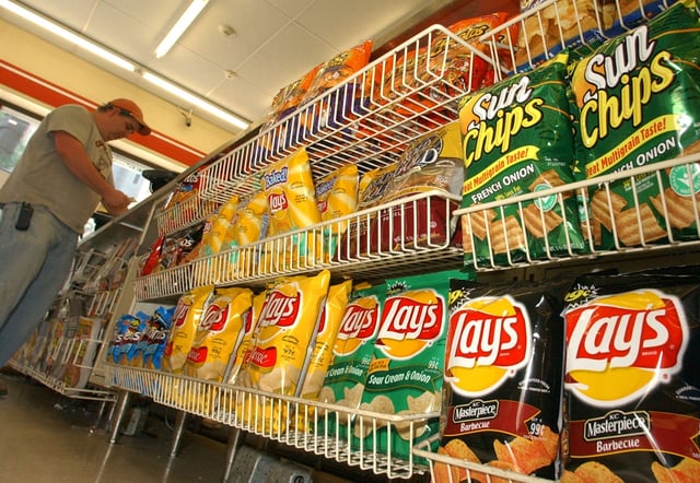 A store customer make a purchase next to a shelf of Frito-Lay snacks. The Food and Drug Administration this week upgraded the recall of Frito-Lay&#39;s Tostitos Cantina-style corn chips to the agency&#39;s most severe classification. 
