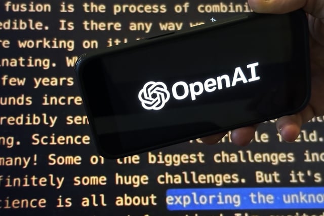 FILE - The OpenAI logo appears on a mobile phone in front of a screen showing part of the company website in this photo taken on Nov. 21, 2023 in New York. (AP Photo/Peter Morgan, File)