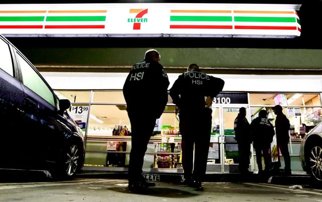 U.S. Immigration and Customs Enforcement agents serve an employment audit notice at a 7-Eleven convenience store in Los Angeles.  Sanctuary laws often prohibit local law enforcement from cooperating with federal immigration officials. (AP file/Chris Carlson)